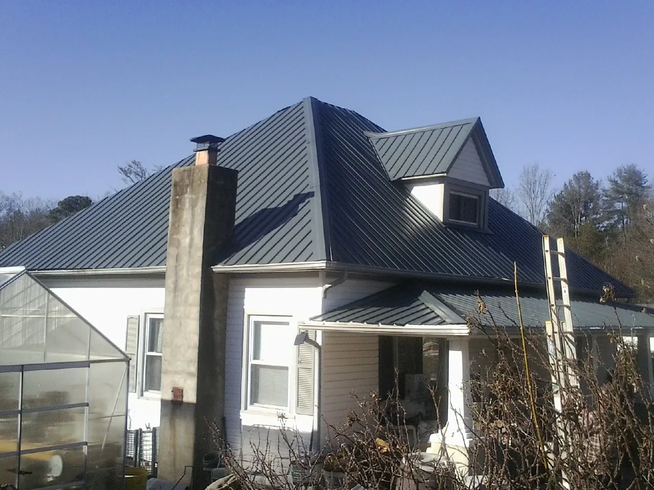 Dark blue standing seam metal roof on a white farmhouse with dormer — Slate & Tile Roof Repair by Roofing Brothers in Ballico
