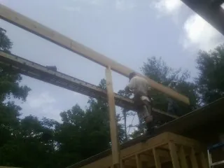 Carpenter setting a ridge beam over a new addition frame — Ice Dam Removal by Roofing Brothers in Ballico