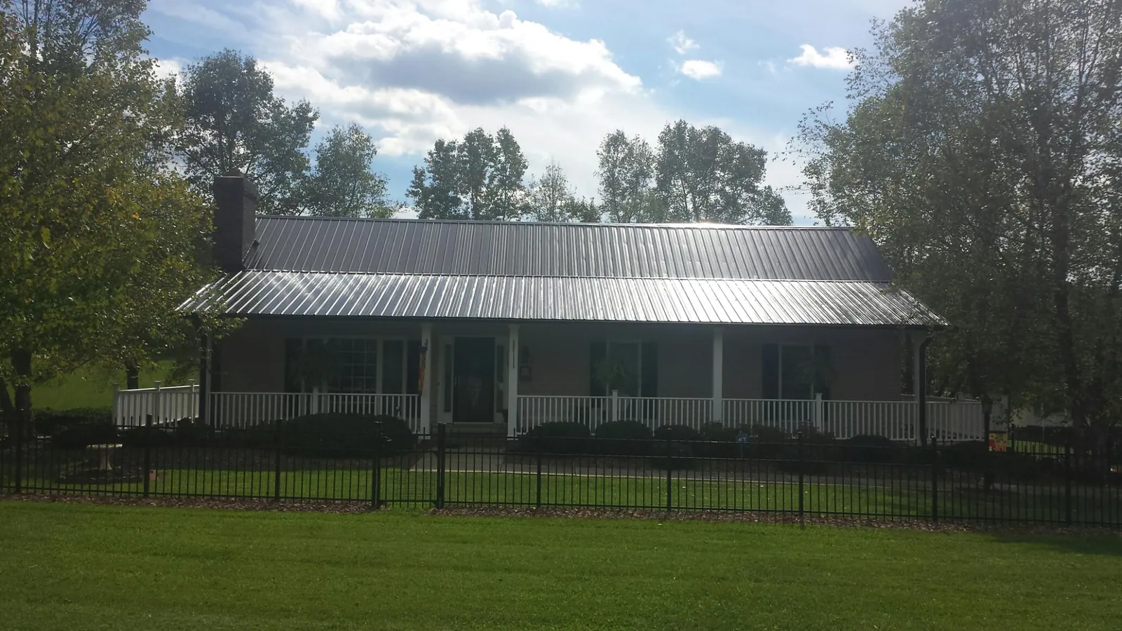 Gray metal roof on a brick ranch with a full width front porch — Gutter Guard Installation work by our crew in Ballico