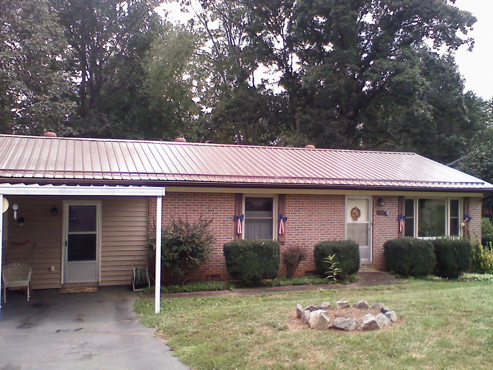 Bronze metal roof and carport on a brick ranch home — Roof Repair work by our crew in Ballico