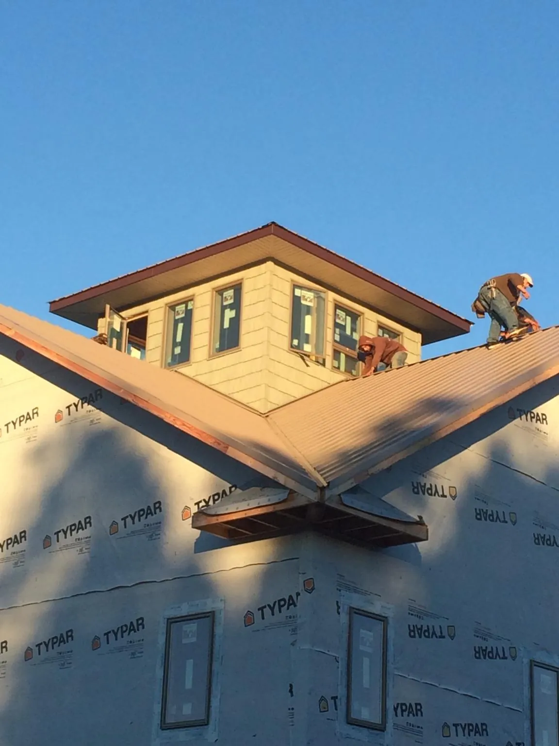 Roofers working around a rooftop cupola on a new metal roof at sunset — Roof Waterproofing in Ballico by Roofing Brothers